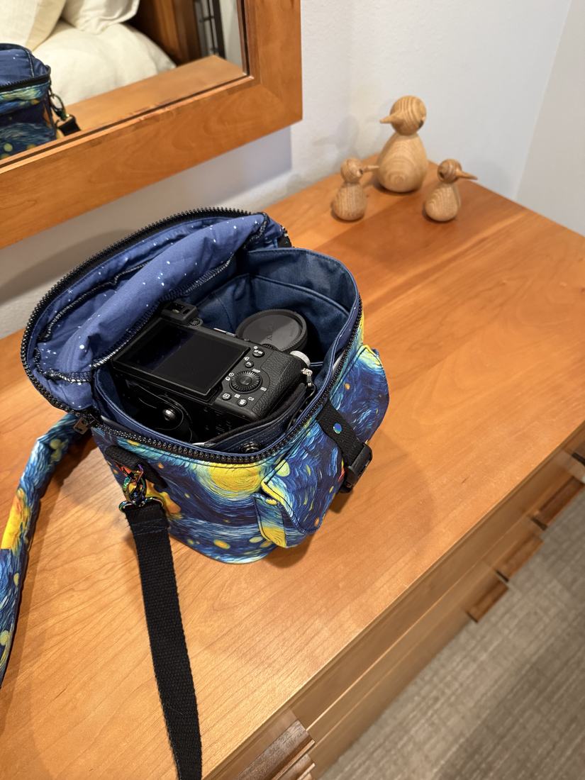 The camera bag open on a wooden dresser with the camera inside.
