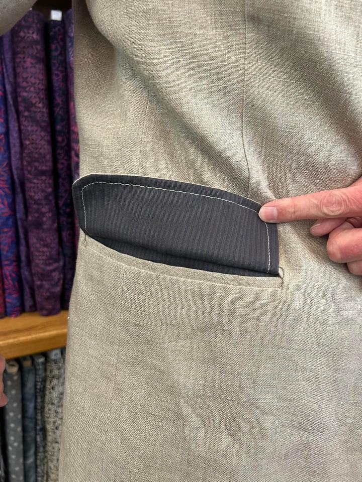 A hip pocket flap lifted to show the striped cotton lining on its underside.