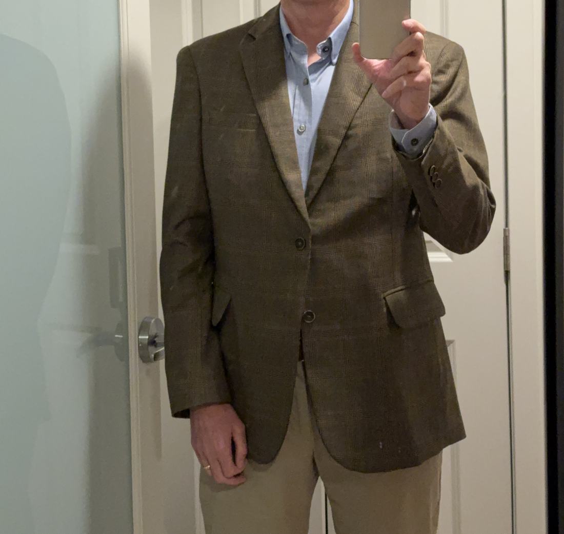 The same glen plaid jacket worn with a blue shirt and tan trousers.