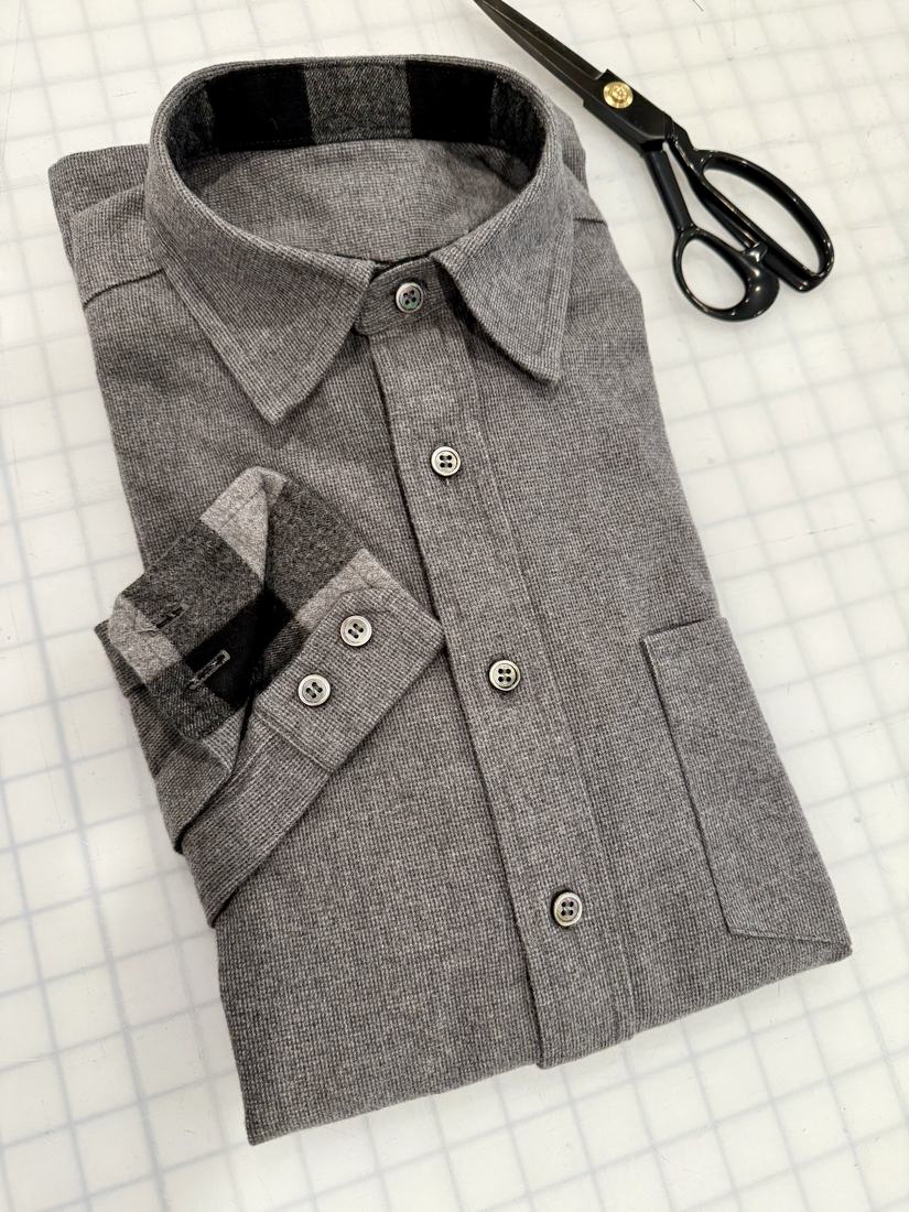 The grey flannel shirt folded on the cutting mat with the cuff turned back to show a contrast facing.