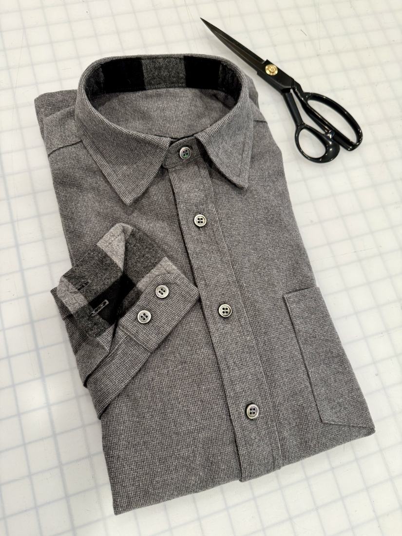 The folded shirt showing the collar and the dark facing inside the stand.